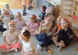 Dzieci z grupy Liski i Motylki i Biedronki siedzą na dywanie.
