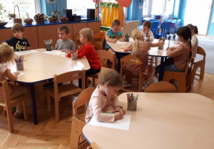 Dzieci z grupy Motylki siedzą przy stolikach i rysują.