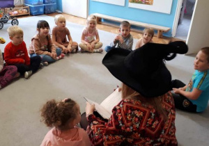 Dzieci z grupy Motylki siedzą na dywanie w kole z autorką książki.