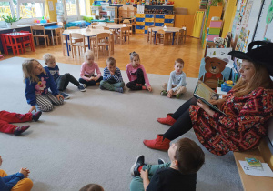 Dzieci z grupy Żabki siedzą na dywanie w kole z autorką książki.