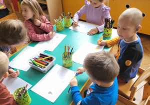 Dzieci z grupy Biedronki siedzą przy stoliku i rysują.