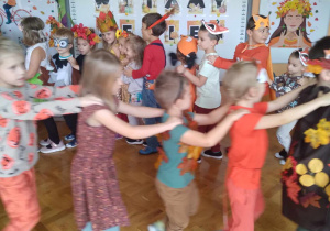 Dzieci tańczą w kole trzymając się za ramiona.