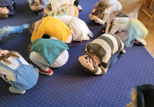 Dzieci leżą na dywanie w towarzystwie psa.