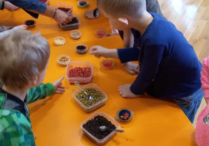 Dzieci stoją dookoła stołów, komponując swoje napoje herbaciane.