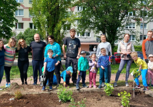 Rodzice, dzieci oraz kadra Przedszkola stoją przed ogródkiem owocowo - warzywnym.