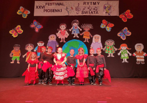 Dzieci stoją na scenie na tle dekoracji festiwalowej.