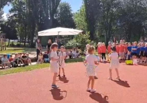 Dziewczynki tańczą na boisku z kolorowymi obręczami.