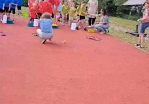 Dzieci wykonują ćwiczenia sportowe na boisku.
