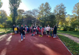 Dzieci stoją na boisku przedszklonym, uczestnicząc w zawodach sportowych.