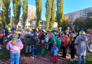 Dzieci stoją na boisku przedszklonym, uczestnicząc w zawodach sportowych.