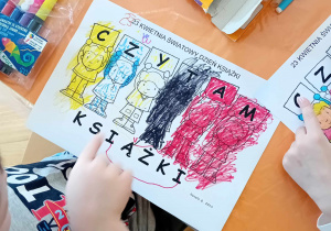 Dzieci kolorują karty pracy z okazji Światowego Dnia Książki.