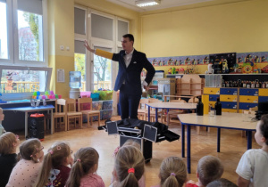 Iluzjonista pokazuje sztuczkę z żółtą rurką na ręce.