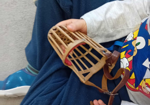 Dziecko siedzi na dywanie i trzyma kaganiec suni Lili.