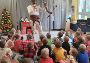 Góral Szczepan prezentuje instrument przed siedzącymi dziećmi.