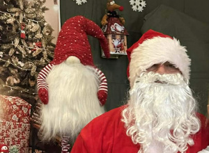 Mikołaj siedzi na krześle na tle świątecznej dekoracji.