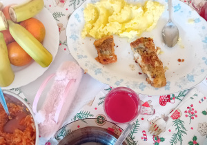 Potrawy stoją na stole świątecznego obiadu (ziemniaki, ryba, owoce).