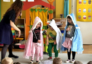 Troje dzieci przebrane za postaci z Lodowej Krainy tańczą z panią Natalią na środku sali, przed nimi siedzą pozostałe dzieci.