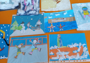 Prace plastyczna "Zimowe zabawy na śniegu" ułożone zbiorczo na stole.