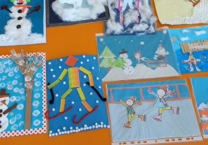 Prace plastyczna "Zimowe zabawy na śniegu" ułożone zbiorczo na stole.