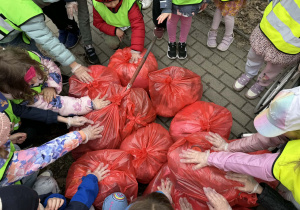 Dzieci stoją dookoła zabranych worków śmieci.
