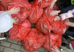 Dzieci stoją dookoła zabranych worków śmieci.