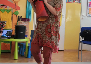 Pani Nutka stoi przed dziećmi, pokazując bęben afrykański.