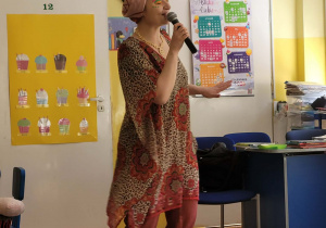 Pani Nutka stoi przed dziećmi, śpiewając piosenkę.