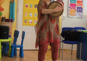 Pani Nutka stoi przed dziećmi, grając na bębnie afrykańskim.