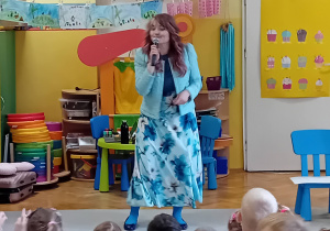 Pani Nutka opowiada dzieciom siedzącym na dywanie o instrumencie muzycznym - flecie.