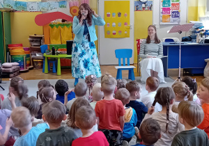 Pani Nutka opowiada dzieciom siedzącym na dywanie o instrumencie muzycznym - flecie.