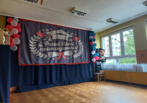 Dekoracja z napisem "Przed Wami Nowe Wyzwania" w sali zakończenia roku przedszkolnego