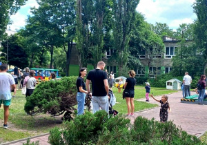Rodzice z dziećmi w ogrodzie przedszkolnym na pikniku rodzinnym.