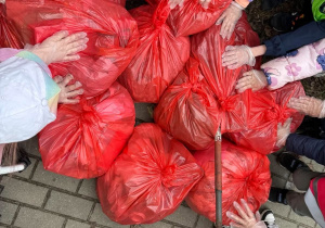 Zebrane worki śmieci, na których są ręce dzieci.