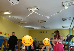 Dzieci stoją na środku sali wykonując z Panią "Nutką' wraz z zaproszonym gościem wspólnie hejnał Łodzi "Prząśniczki".