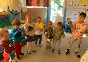 Marzec. Realizacja Innowacji pedagogicznej "Słucham , Czuję, Analizuję Poezję - Wspieranie Rozwoju Małego Dziecka". Dzieci stoją na dywanie, trzymają kukiełki. Inscenizują wiersz J. Brzechwy "Katar"