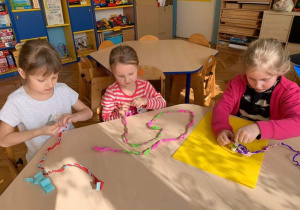 W ramach projektu serdeczna karteczka dzieci wykonują kartki na "Dzień Piekarza i Cukiernika". Trzy dziewczynki zwijają paski bibuły.