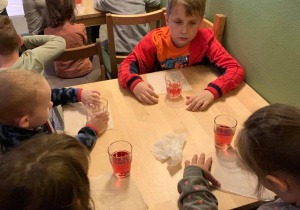 Grupa I. Wycieczka do Baśniowej Kawiarenki. Dzieci piją soczek przy stolikach.