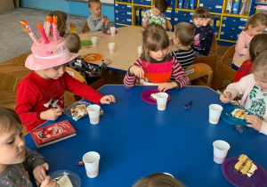 8 urodziny Gabrysia. Dzieci siedzą przy stolikach. Jedzą tort i piją soczek z jednorazowych kubeczków.