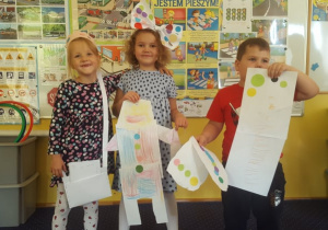 Troje dzieci prezentuje swoje prace zaprojektowane w ramach Dnia Kropki.