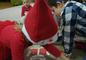 Na zdjęciu widać dzieci pomagające ubrać się Mikołajowi.