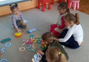 W świecie kosmosu - dzieci siedząc na dywanie, rozwiązuje rebus, którego rozwiązaniem jest "kosmos".