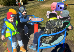 Zabawy dzieci na karuzeli w ogródku przedszkolnym.
