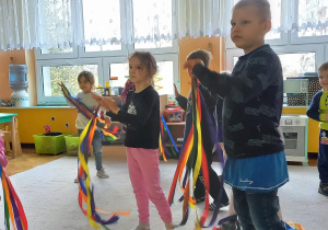 Taniec dzieci na dywanie z kolorowymi szarfami.